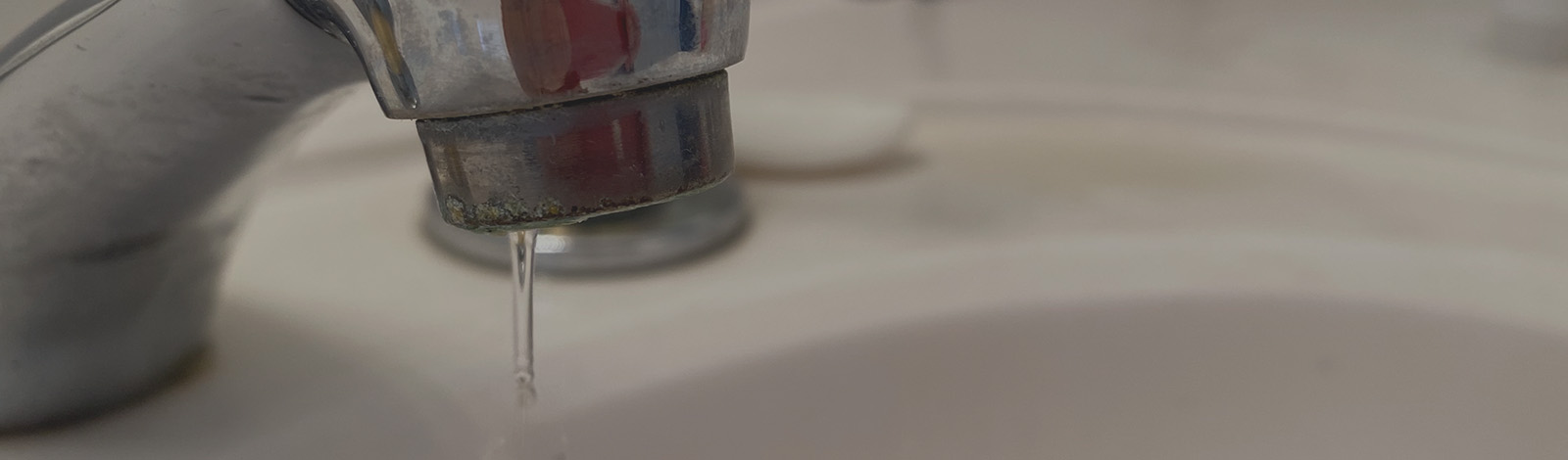 A close up of a leaking sink faucet.