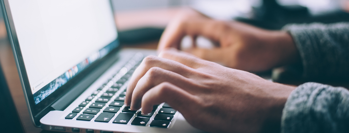 a person typing on a macintosh laptop